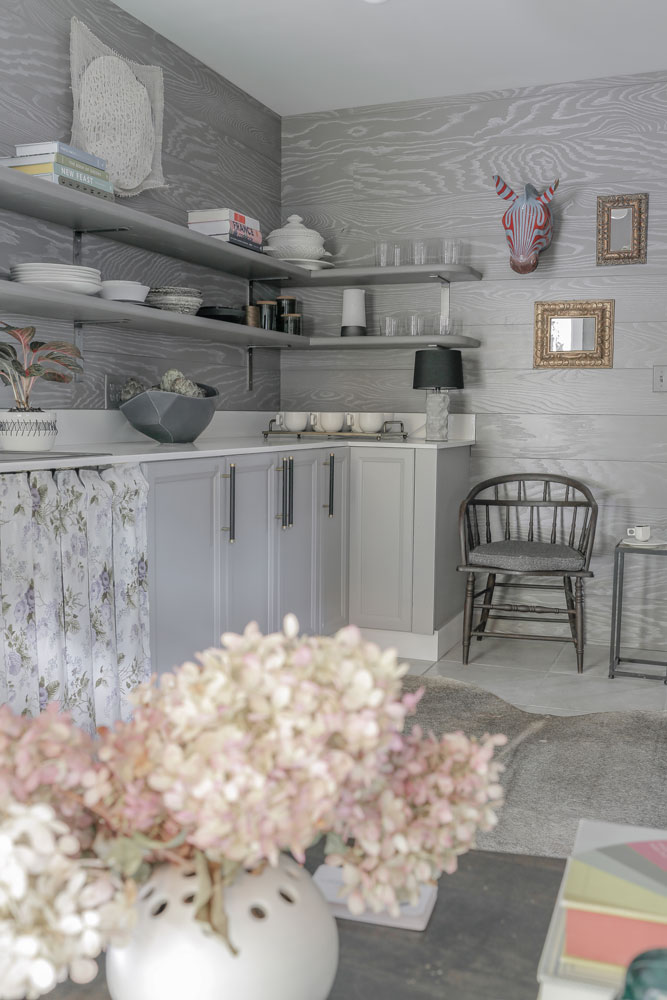 interior room with grey wood paneling and light tiled floors. grey cabinets and wall shelves around the perimeter