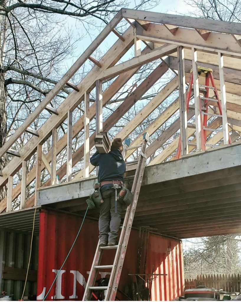 two shipping containers with wooden beams for a roof