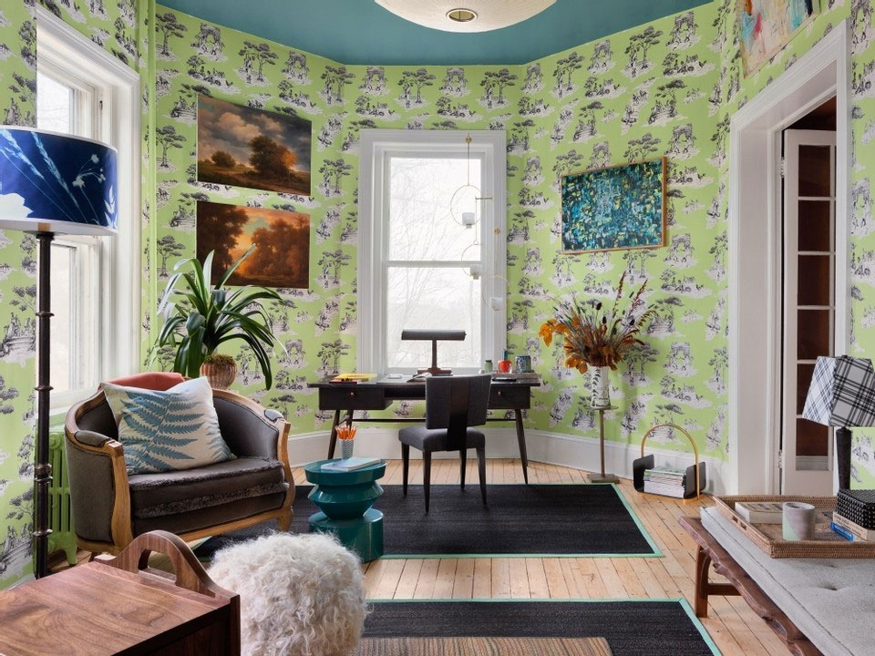 large room with desk, chair, rugs and green illustrative wallpaper with windows
