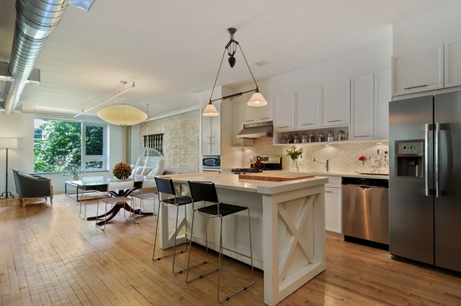 White kitchen island with barstools and hanging lights