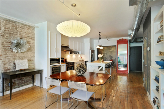 interior room with dining table and chairs, modern kitchen, with brick walls and light wood floors