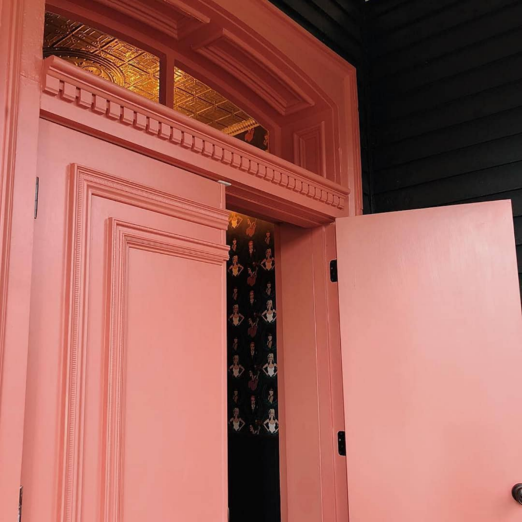 exterior coral pink door opened to show wallpaper print inside entryway